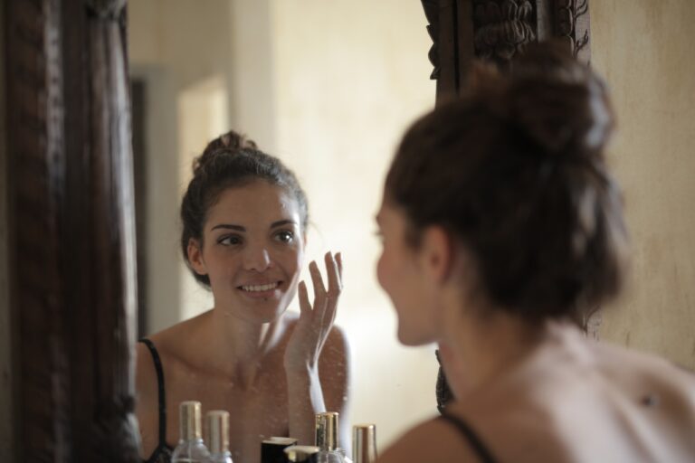 Kobieta nakłada na twarz krem z witamina C przed lustrem w dużej łazience